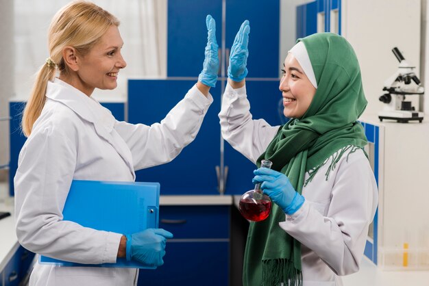 Vue de côté de femmes scientifiques dans le laboratoire se faisant mutuellement plaisir