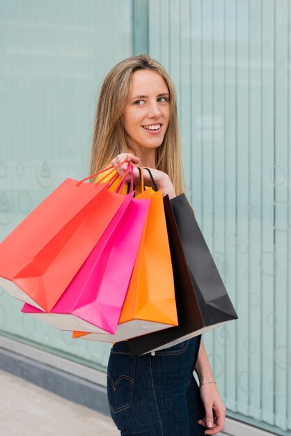 Vue de côté fille avec des sacs à provisions à la recherche de suite