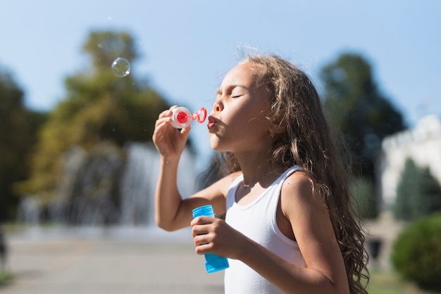 Vue de côté d'une fille soufflant des bulles