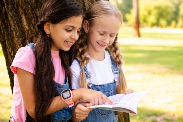 Vue de côté des filles à côté de la lecture des arbres