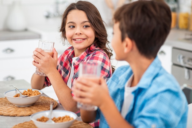 Photo gratuite vue de côté des frères et sœurs buvant du jus de fruits frais