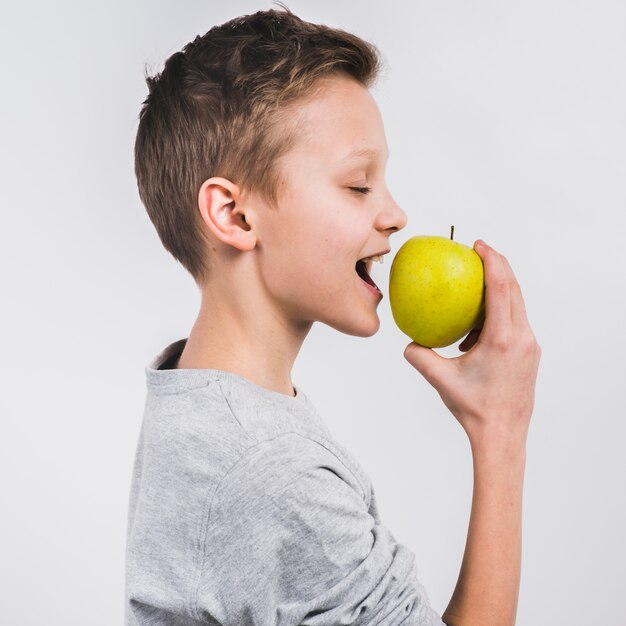 Vue côté, de, a, garçon mange, vert frais, pomme, isolé, sur, blanc, fond