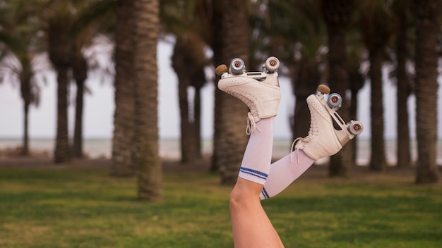 Photo gratuite vue de côté de la jambe d'une femme portant des patins à roulettes blanches contre l'arbre