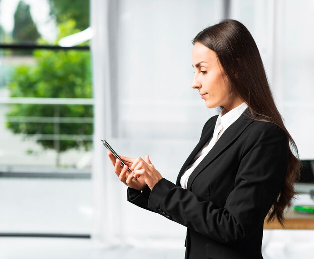 Vue de côté d&#39;une jeune femme d&#39;affaires à l&#39;aide de smartphone