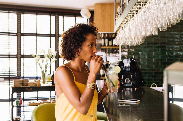 Vue côté, de, jeune femme, boire cocktail, à, comptoir