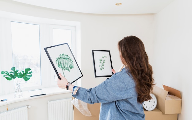 Vue de côté d&#39;une jeune femme choisissant un cadre photo pour sa nouvelle maison