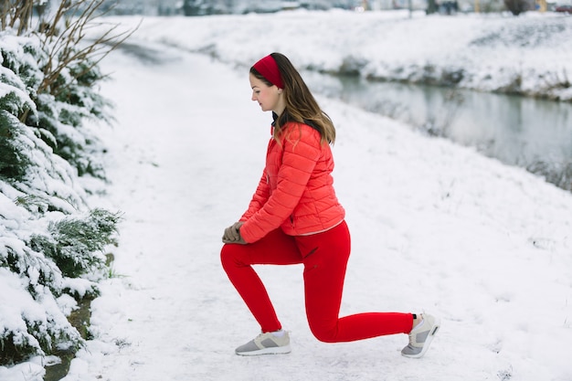 Vue de côté de la jeune femme qui s&#39;étend de la jambe en hiver