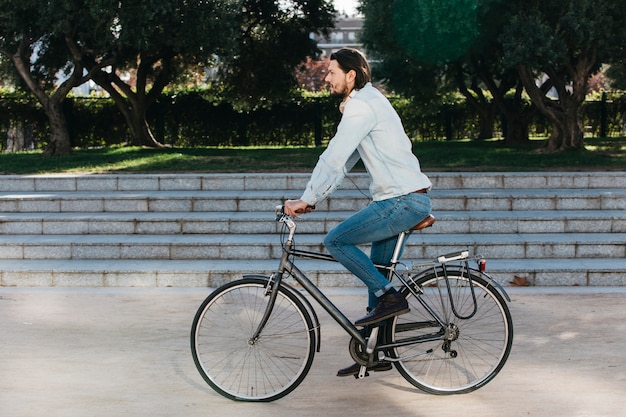 Vue de côté d&#39;un jeune homme à vélo dans le parc