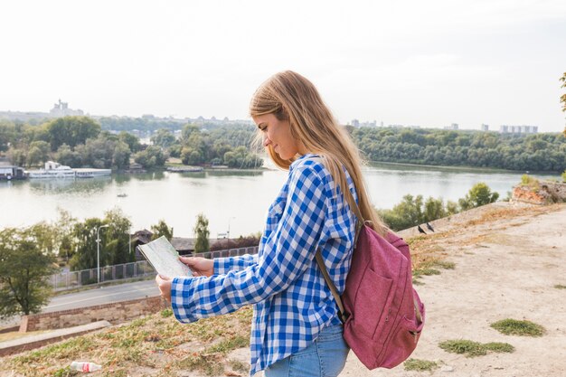 Vue de côté d&#39;une jeune randonneuse à la recherche de sens sur la carte