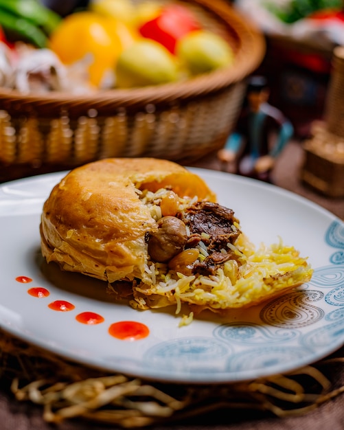 Vue de côté khan pilaf riz au safran moucheté enveloppé dans du lavash saturé de beurre avec de la viande de boeuf, des raisins châtaignes et des abricots secs