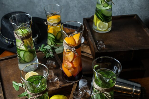 Vue de côté mélanger de l'eau de désintoxication avec des pommes au citron menthe et concombre dans des carafes