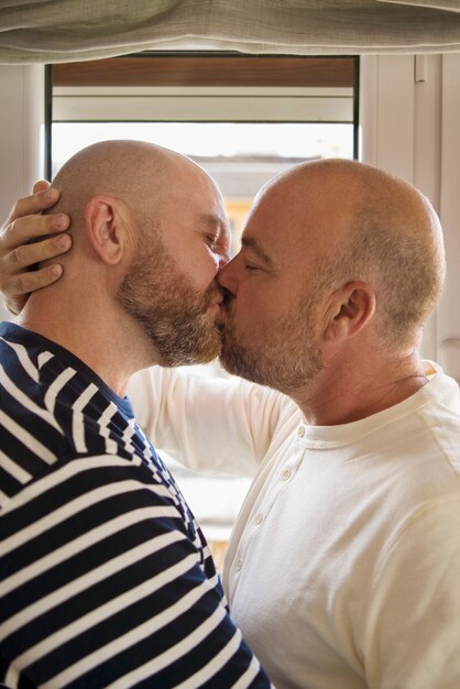 Vue de côté partenaires homosexuels s'embrassant à la maison