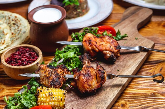 Vue de côté poulet kebab avec tomates vertes oignon rouge séché, épine-vinette et yogourt sur la table