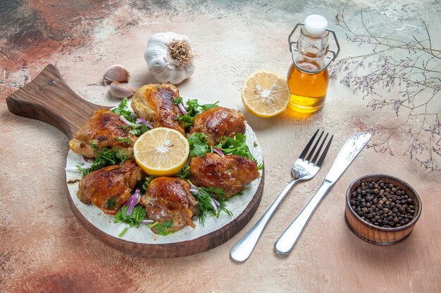 Vue de côté poulet poulet aux herbes oignon citron sur la planche couteau fourchette huile ail poivre noir