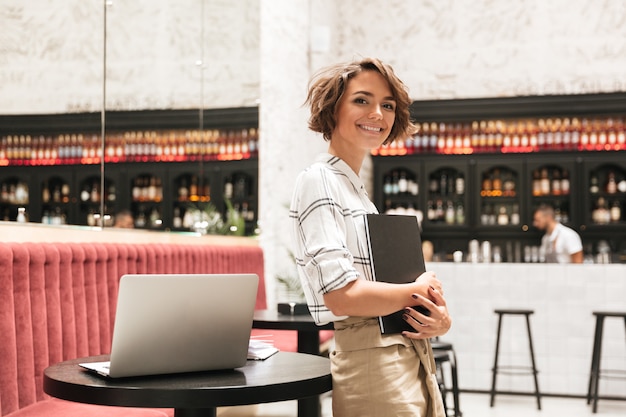 Vue côté, de, sourire, bouclé, femme, debout, table