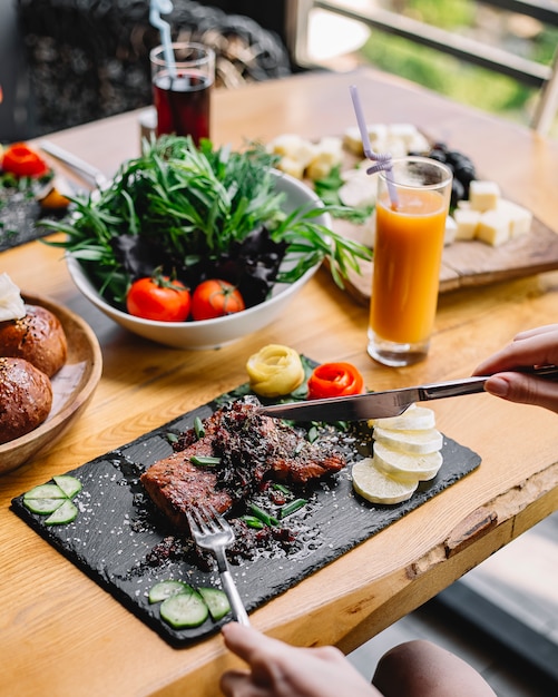 Vue de côté steak grillé viande rouge concombre tomate et citron sur une planche