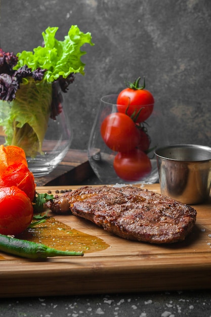 Vue de côté steak avec tomate et papier en planche à steak