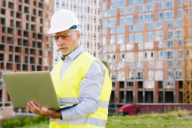 Vue de côté vieil homme avec ordinateur portable à l'extérieur