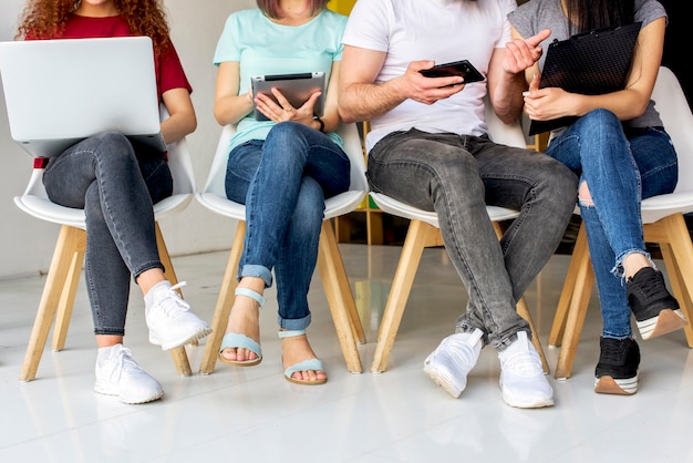 Vue en coupe basse de personnes assises sur une chaise à l&#39;aide d&#39;appareils sans fil