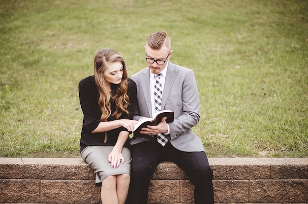 Vue d'un couple lisant et discutant d'un livre assis dans un jardin