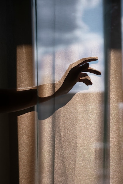 Photo gratuite vue créative des mains avec des rideaux et des ombres depuis la fenêtre