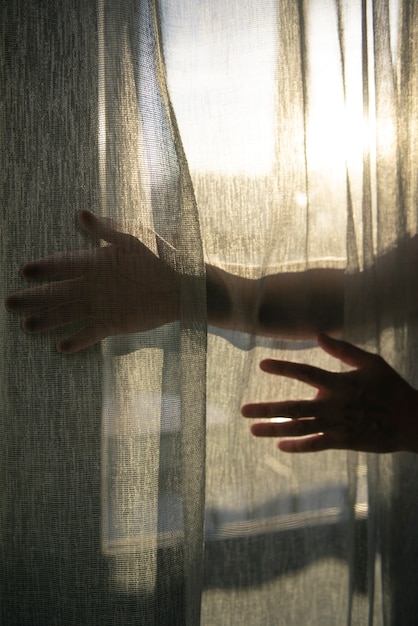 Photo gratuite vue créative des mains avec des rideaux et des ombres depuis la fenêtre