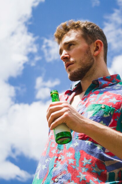 Vue de dessous blonde garçon tenant une bière