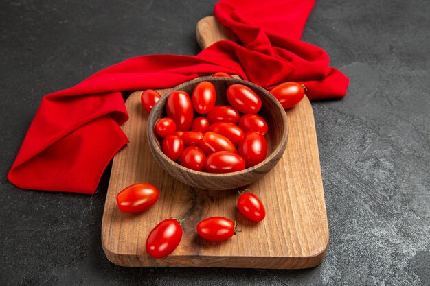 Vue de dessous bol avec tomates cerises et serviette rouge sur une planche à découper sur fond sombre