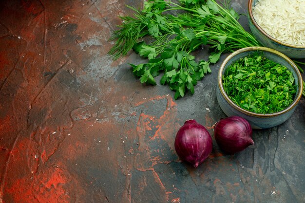 Vue de dessous des bols avec du riz vert haché, du persil, des oignons rouges sur une table rouge foncé avec un lieu de copie