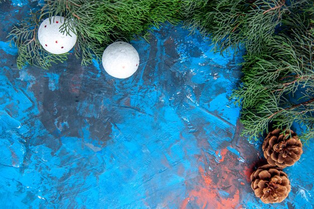 Vue de dessous branches de pin pommes de pin jouets d'arbre de Noël blanc sur fond bleu-rouge avec espace libre