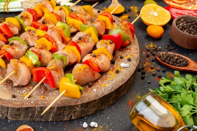 Vue de dessous des brochettes de poulet cru sur une planche de bois naturel et d'autres trucs sur un tableau noir