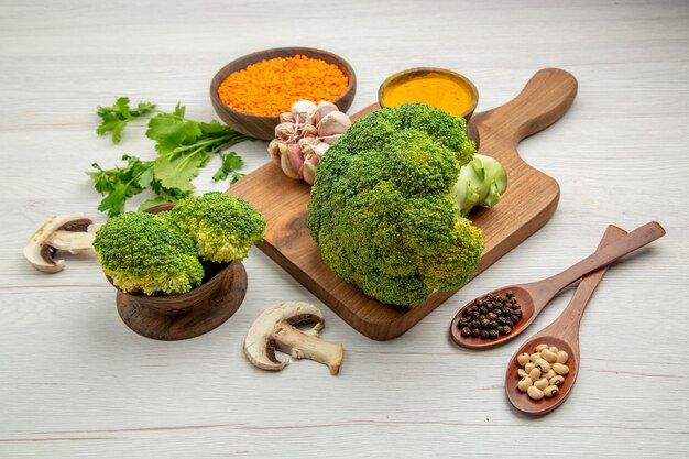 Vue De Dessous Brocoli Ail Curcuma Frais Sur Planche à Découper Champignons Bol Lentilles Persil Cuillères En Bois Sur Table Grise