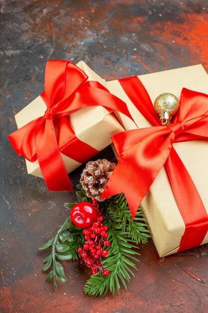Vue de dessous des cadeaux de Noël attachés avec une branche d'arbre de Noël de ruban rouge sur fond rouge foncé