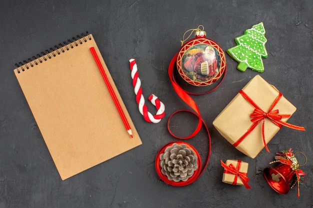 Photo gratuite vue de dessous cadeaux de noël en ruban de papier brun jouet d'arbre de noël sur papier journal sur dark