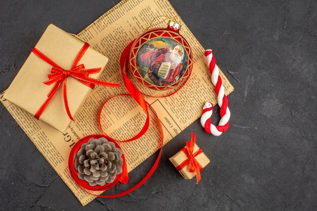 Vue de dessous cadeaux de Noël en ruban de papier brun jouet d'arbre de Noël sur papier journal sur dark