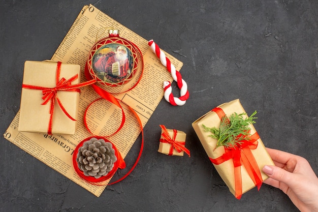 Vue de dessous cadeaux de Noël en ruban de papier brun jouet d'arbre de Noël sur papier journal sur fond sombre