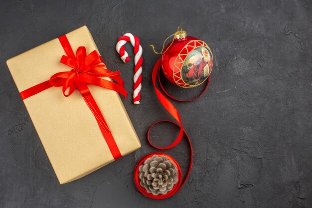 Vue de dessous cadeaux de Noël en ruban de papier brun jouet d'arbre de Noël sur papier journal sur fond sombre