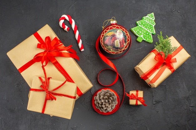 Vue de dessous cadeaux de Noël en ruban de papier brun jouet d'arbre de Noël sur papier journal sur fond sombre