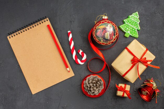 Vue de dessous cadeaux de Noël en ruban de papier brun jouet d'arbre de Noël sur papier journal sur fond sombre