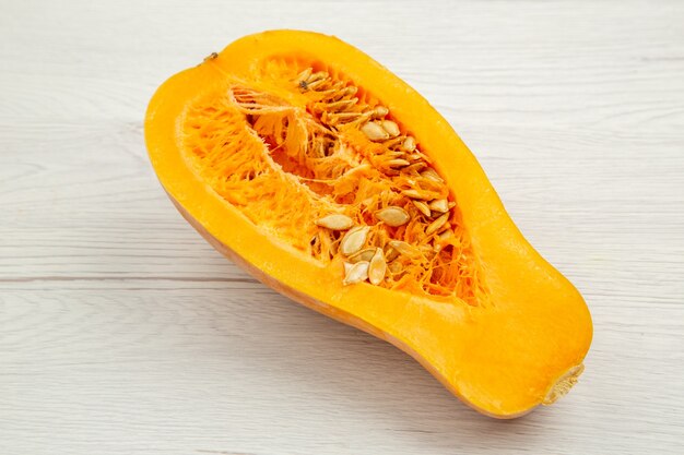 Vue de dessous de la courge musquée coupée en deux sur un espace libre de table en bois blanc