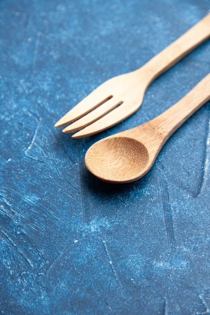 Photo gratuite vue de dessous cuillère fourchette en bois sur surface bleue