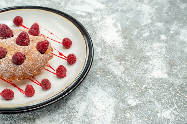 Vue de dessous du gâteau aux baies sur une assiette ovale blanche sur une surface grise avec espace de copie