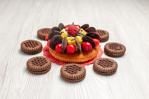 Vue De Dessous Gâteau Aux Baies Sur Le Napperon En Dentelle Ovale Rouge Et Biscuits Sur La Table En Bois Blanc