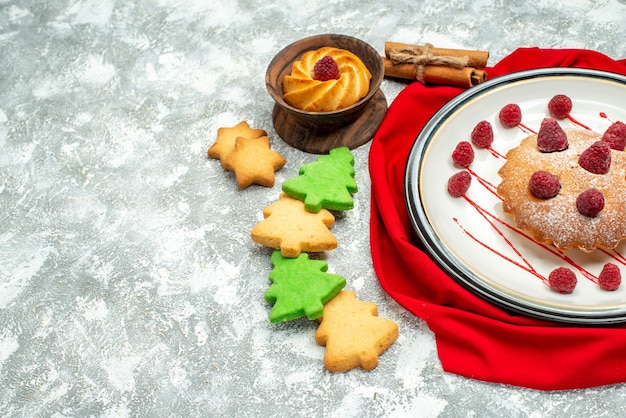 Photo gratuite vue de dessous gâteau aux baies sur plaque ovale blanche biscuits châle rouge sur espace libre de surface grise