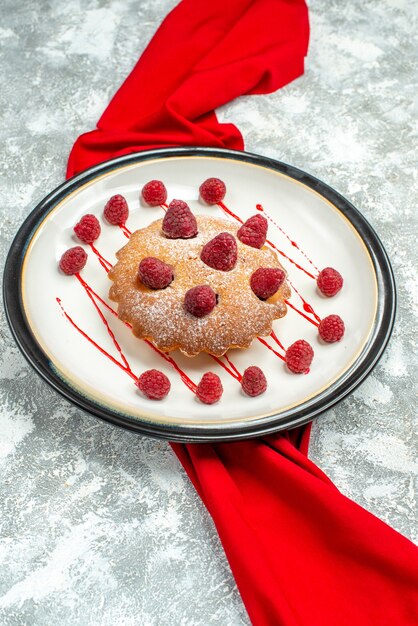 Vue de dessous gâteau aux baies sur plaque ovale blanche châle rouge sur surface grise