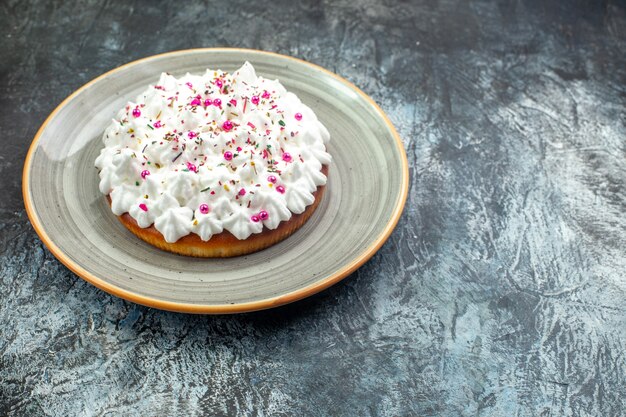 Vue de dessous gâteau avec crème pâtissière sur plateau rond gris sur table grise