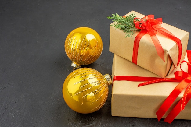 Vue de dessous grands et petits cadeaux de Noël en papier brun attaché avec des boules de Noël en ruban rouge sur noir
