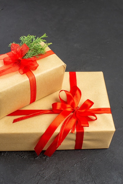 Vue de dessous grands et petits cadeaux de Noël en papier brun attaché avec du sapin de branche de ruban rouge sur fond sombre
