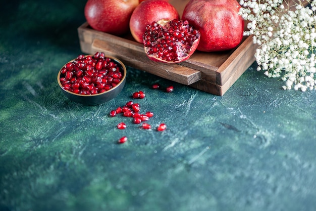 Vue de dessous grenades fraîches sur planche de bois fleurs sur table espace libre