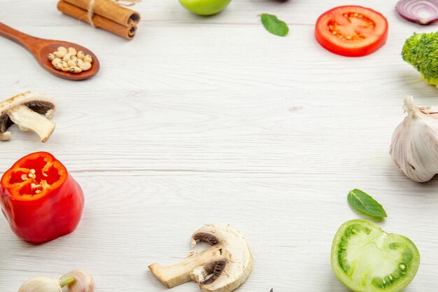 Vue de dessous légumes coupés cuillère en bois bâtons de cannelle et autres trucs sur table grise avec espace libre